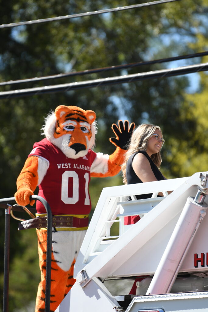 Luie the Tiger waves to parade onlookers
